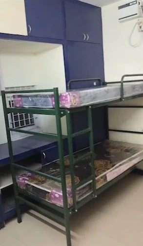 Bunk bed beside blue built-in cabinets with an air conditioner on the wall
